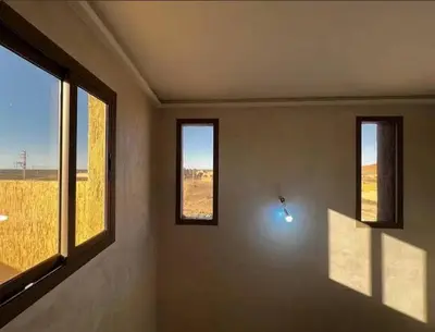 a room with three windows and a view of a field at merzouga apartment in Merzouga