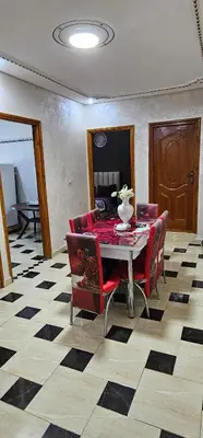 a dining room with a table and red chairs at Appartement lumineux avec vue panoramique in Meknès