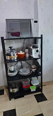 a shelf filled with pots and pans and a microwave at Appartement lumineux avec vue panoramique in Meknès
