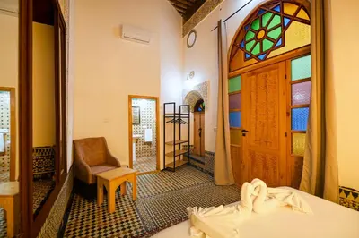a room with a bed and a door and a chair at Riad Les Émeraudes De Fes in Fès