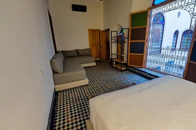 a bedroom with a bed and a couch and a window at Riad Les Émeraudes De Fes in Fès