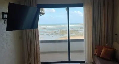 a room with a large window with a view of the ocean at Appartement avec vue panoramique sur la mer, climatisation, terrasse & ascenseur in Oulad Akkou