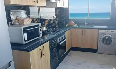 a kitchen with a microwave and a stove top oven at Appartement avec vue panoramique sur la mer, climatisation, terrasse & ascenseur in Oulad Akkou