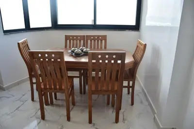 a dining room table with four chairs and a bowl of fruit at Appartement avec vue panoramique sur la mer, climatisation, terrasse & ascenseur in Oulad Akkou