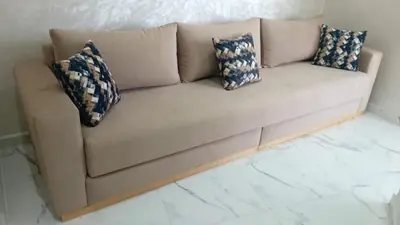 a couch with pillows on it in a living room at Appartement avec vue panoramique sur la mer, climatisation, terrasse & ascenseur in Oulad Akkou