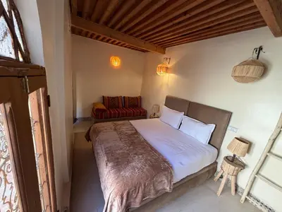 a bedroom with a bed and a red chair at Dar Al Rcif in Station Bab Ftouh