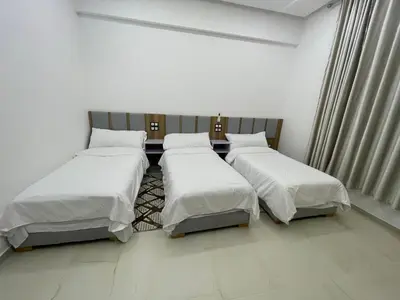 three beds in a room with white walls at Hotel kairouan in Fès