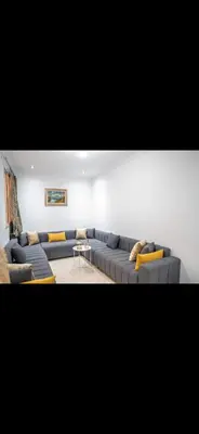 a living room with a blue couch and yellow pillows at Appartement très spacieux au coeur de Temara à 10 minutes du grand stade de Rabat in Oulad Akkou