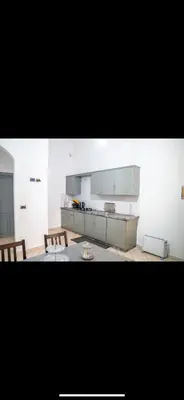 a kitchen with white cabinets and two benches in a room at Appartement très spacieux au coeur de Temara à 10 minutes du grand stade de Rabat in Oulad Akkou