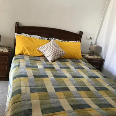 a bed with two yellow pillows and a blanket at Central, modern and well-equipped apartment in Oulad Akkou