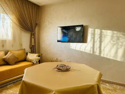 a living room with a table and a couch at Central, modern and well-equipped apartment in Oulad Akkou