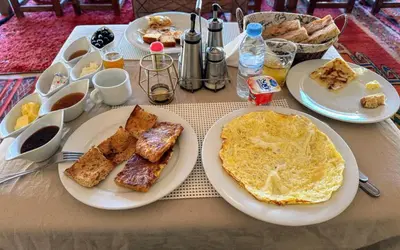 a table with plates of breakfast food on it at Infinite Sky Luxury Camp Merzouga in Merzouga
