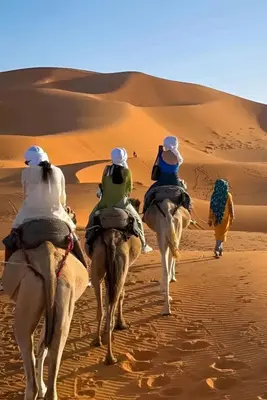 three people riding on camels in the desert at Infinite Sky Luxury Camp Merzouga in Merzouga