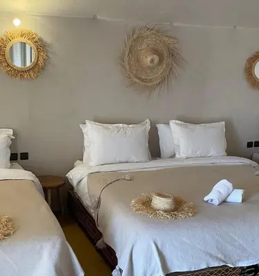 a bedroom with two beds with towels and mirrors at Morocco Sahara Desert Camp in Merzouga