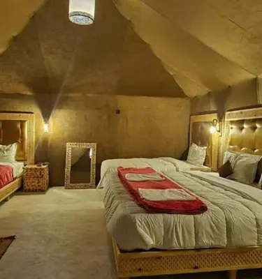 a bedroom with a large bed and a mirror at Morocco Sahara Desert Camp in Merzouga