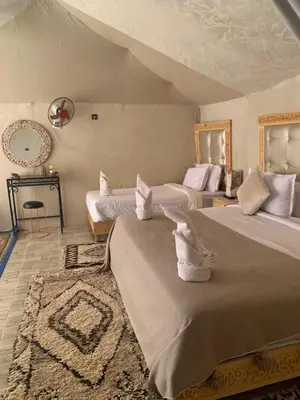 a large bedroom with two beds and a rug at Morocco Sahara Desert Camp in Merzouga
