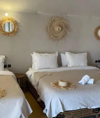 a bedroom with two beds with white sheets and two mirrors at Morocco Sahara Desert Camp in Merzouga