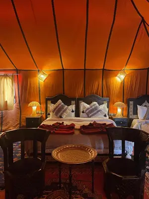a room with a bed and two chairs and a table at luxury camp Oasis Opal in Merzouga