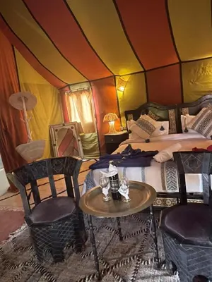 a room with two beds and a table and chairs at luxury camp Oasis Opal in Merzouga
