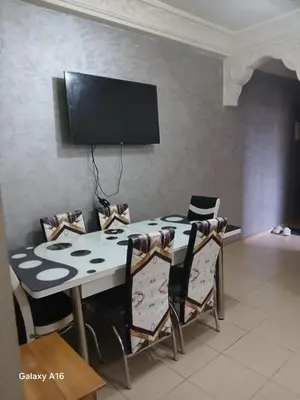a dining room table with chairs and a flat screen tv at jardaine d'Ifrane in Ifrane