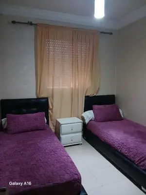 two beds in a room with purple sheets and a window at jardaine d'Ifrane in Ifrane