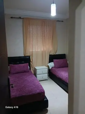 a bedroom with two beds with purple sheets and a window at jardaine d'Ifrane in Ifrane