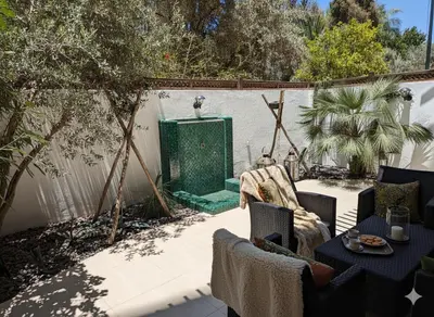 a patio with a table and chairs and a fountain at Superbe appartement duplex à l'hivernage in Oulad Akkou