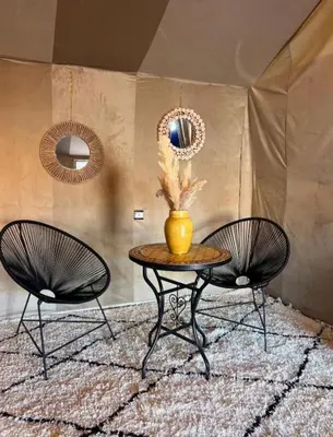 two chairs and a table with a vase on it at Luxury Stars Camp in Merzouga