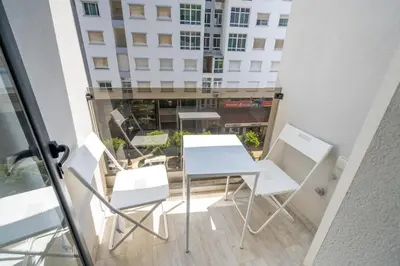 a table and chairs on a balcony with a building at Chic Beachfront Studio Appartment in Oulad Akkou