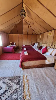 a bedroom with two beds in a tent at sahara desert camp in Merzouga