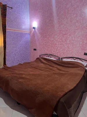 a bedroom with a bed with a brown blanket at Merzouga Roms in Merzouga