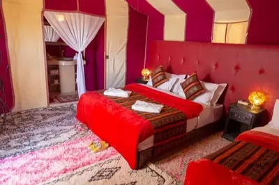 a bedroom with a bed with a red head board at Merzouga Dream Camp in Merzouga