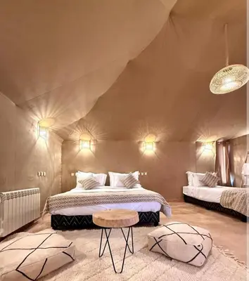 a bedroom in a tent with a bed and a table at Merzouga Dream Camp in Merzouga