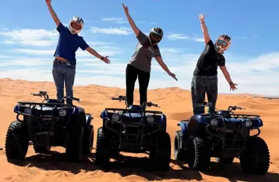 four people standing on atvs in the desert at Merzouga Dream Camp in Merzouga