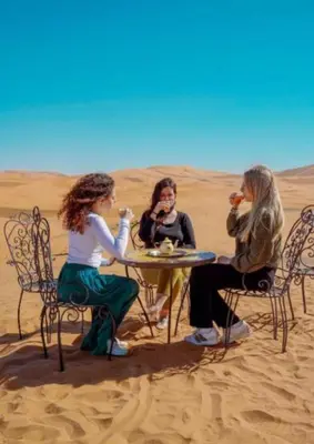 three women sitting at a table in the desert at Merzouga Dream Camp in Merzouga