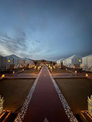 a long walkway in a parking lot with tents at beststaysbylocal in Merzouga