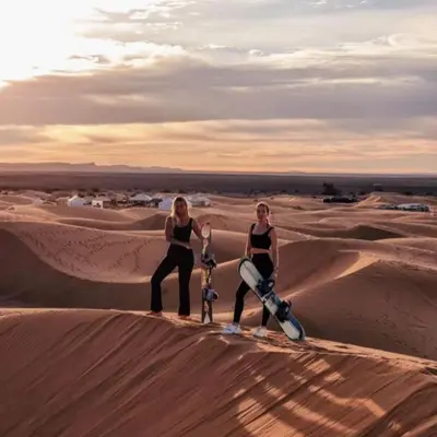two women standing on the sand dunes in the desert at Best Merzouga traductional camp in Merzouga