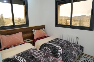 two beds in a room with two windows at Gite Atlas Tigrigra