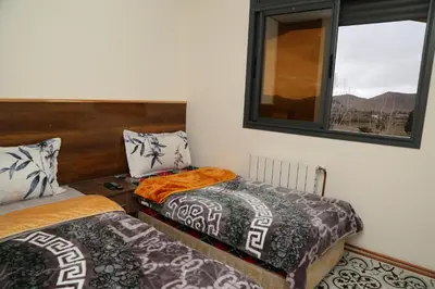 two beds in a room with two windows at Gite Atlas Tigrigra