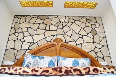 a bedroom with a wooden bed with a stone wall at Gite Atlas Tigrigra