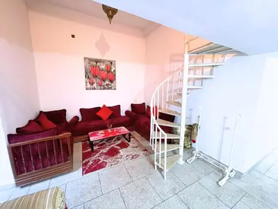 a living room with a red couch and a staircase at ZenStay Residences Modern Apartments Near City Center With Balcony And Wifi in Fès