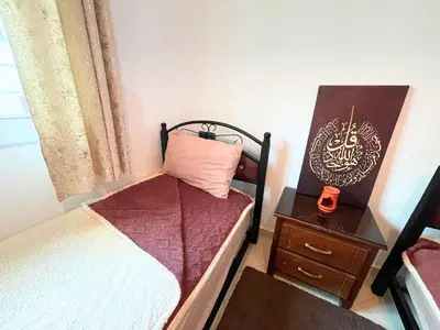a small bedroom with two beds and a night stand at ZenStay Residences Modern Apartments Near City Center With Balcony And Wifi in Fès