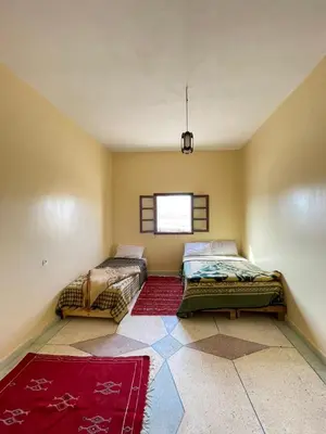 a bedroom with two beds and a window at Maison zahra merzouga in Merzouga