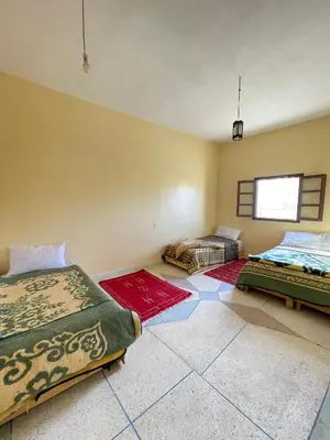 a room with two beds and rugs on the floor at Maison zahra merzouga in Merzouga