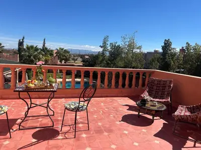 a patio with chairs and tables on a balcony at Private pool villa & garden Marrakech in Marrakech
