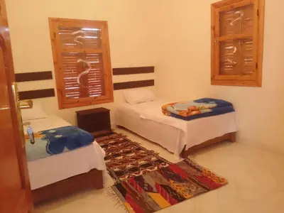 a room with two beds and a window and a rug at Kasbah Anisi