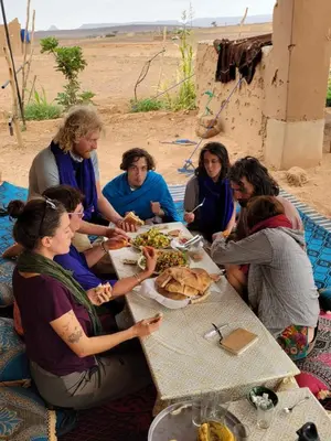 a group of people sitting around a table eating food at Authentic Sahara with Locals in Tagounite