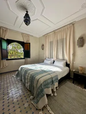 a bedroom with a bed and a chandelier at Villa Atika - Maison d'Hôtes & SPA in El Bougaria