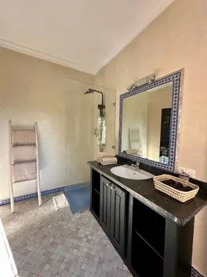 a bathroom with a sink and a mirror and a chair at Villa Atika - Maison d'Hôtes & SPA in El Bougaria