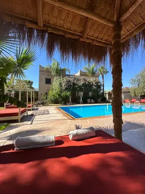 a bed under a pavilion with a swimming pool at Villa Atika - Maison d'Hôtes & SPA in El Bougaria